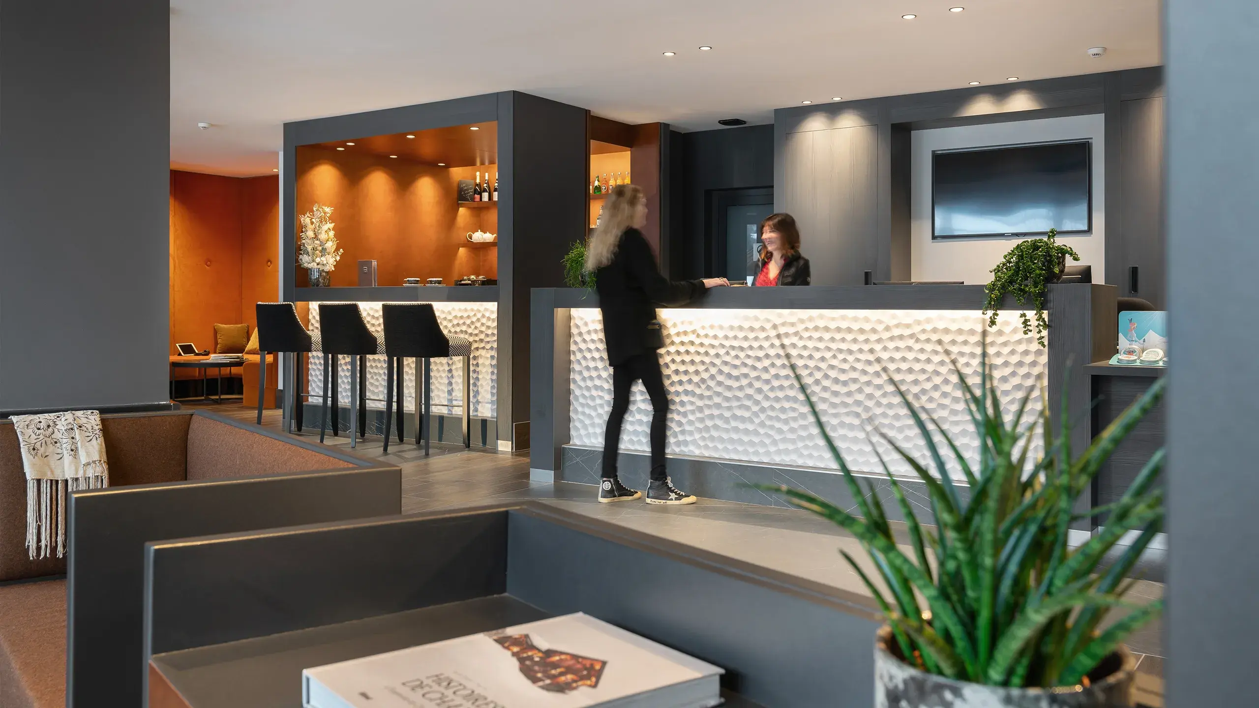 Une personne est au comptoir de la réception des Chalets Láska aux Contamines-Montjoie