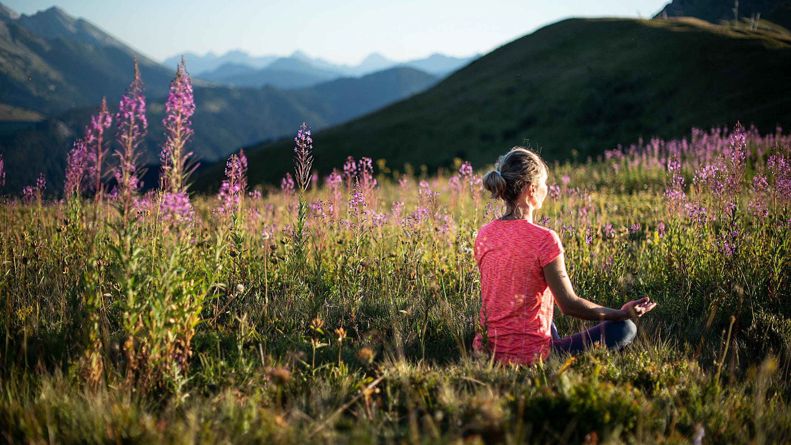 Femme faisant du yoga dans un champ au coeur des Aravis