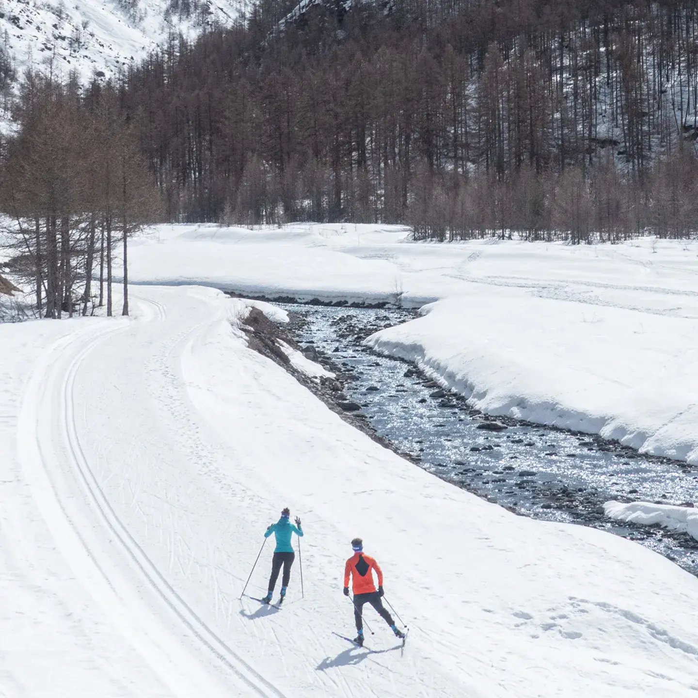 Deux personnes font du ski nordique le long d'un cours d'eau en Haute Maurienne