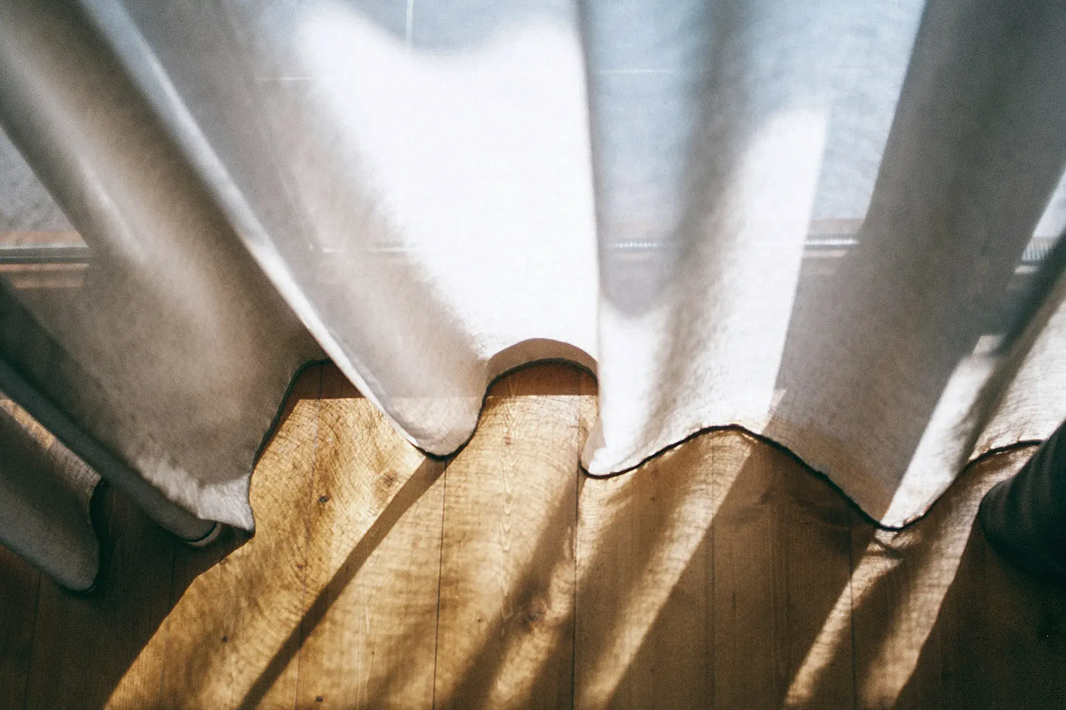 soleil qui entre par les rideaux d'une baie vitrée 