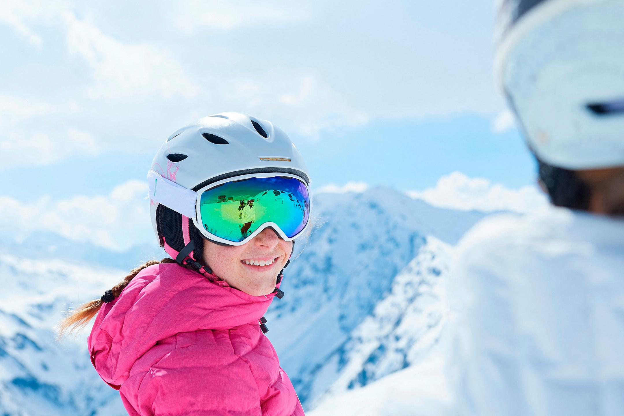 enfant avec équipement de ski face à un paysage enneigé