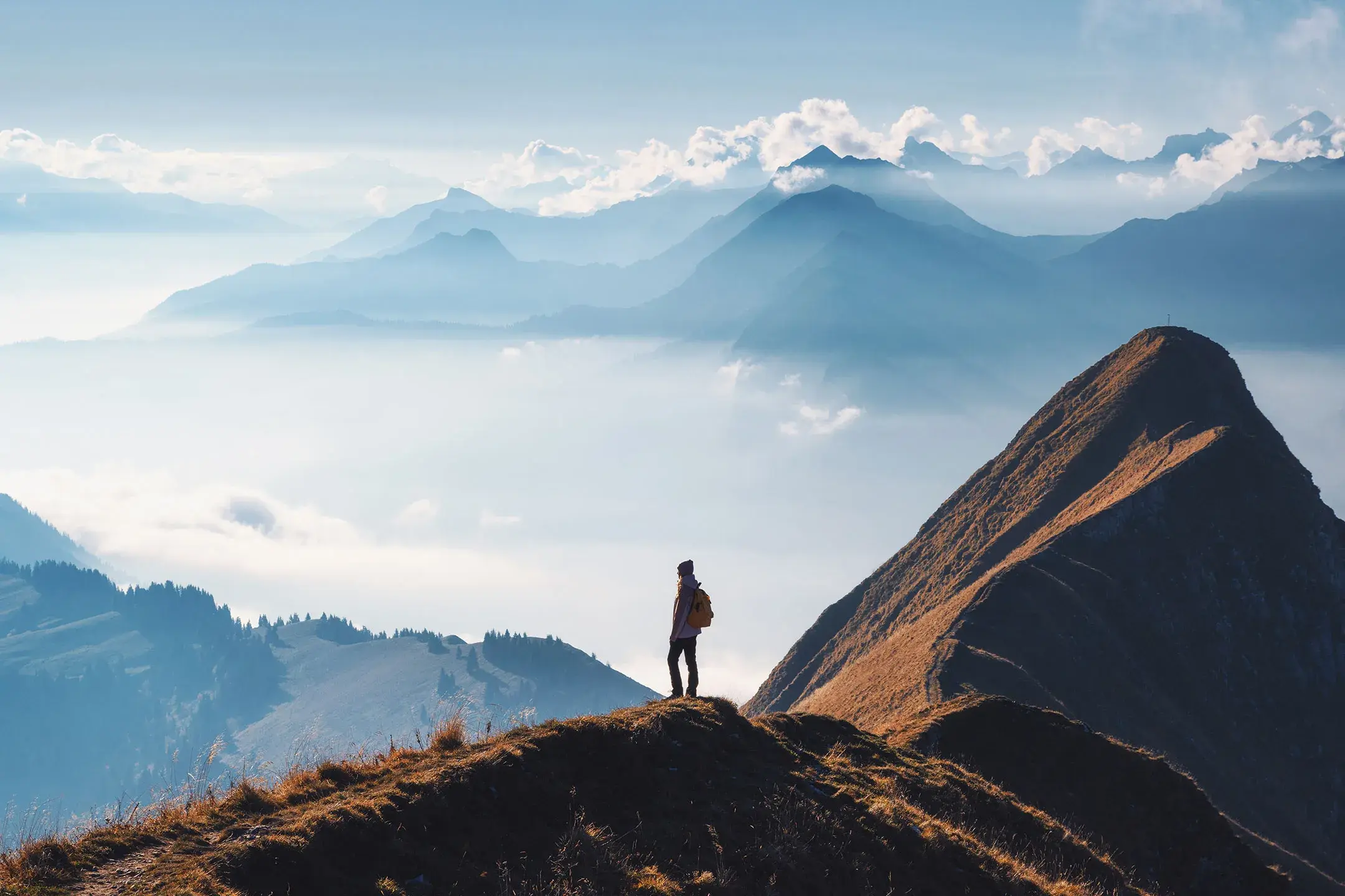 Une personne en randonnée admire la vue depuis la crête d'une montagne