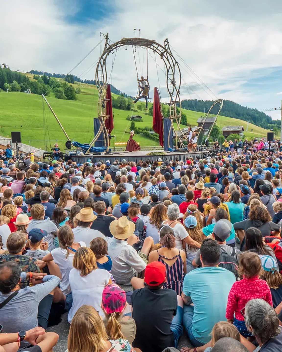 Une foule de spectateurs regarde 2 artistes effectués un spectacle de cirque  lors de l'évènement annuel aux Bonheur des Mômes au Grand-Bornand
