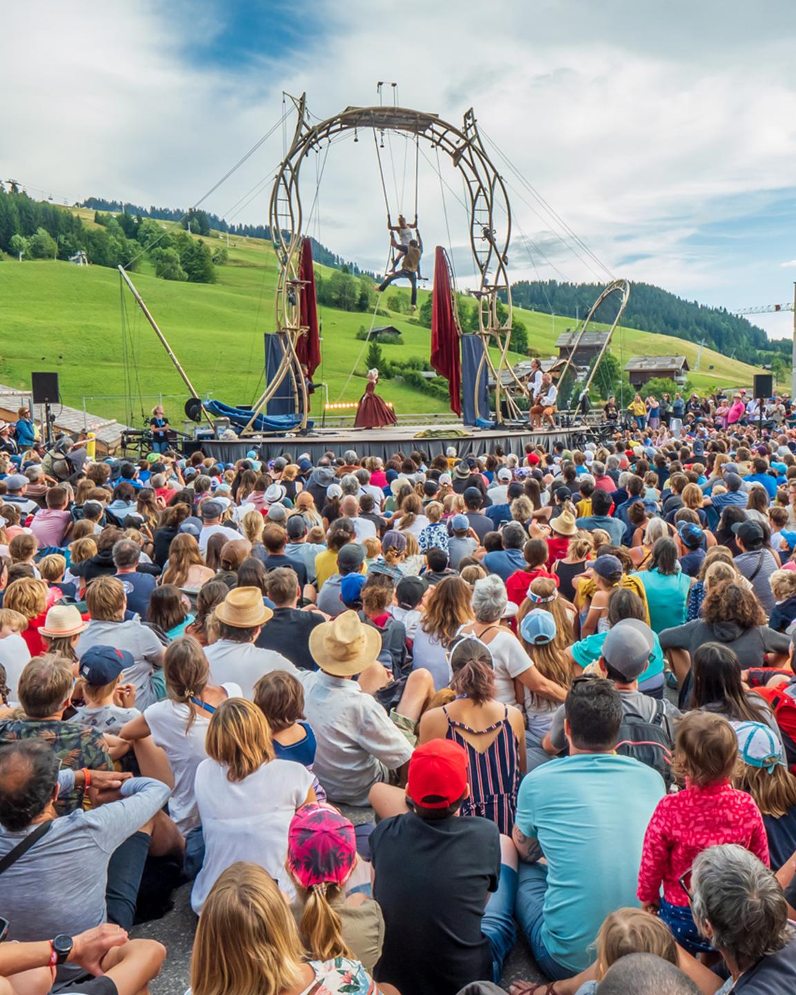Une foule de spectateurs regarde 2 artistes effectués un spectacle de cirque lors de l'évènement annuel aux Bonheur des Mômes au Grand-Bornand