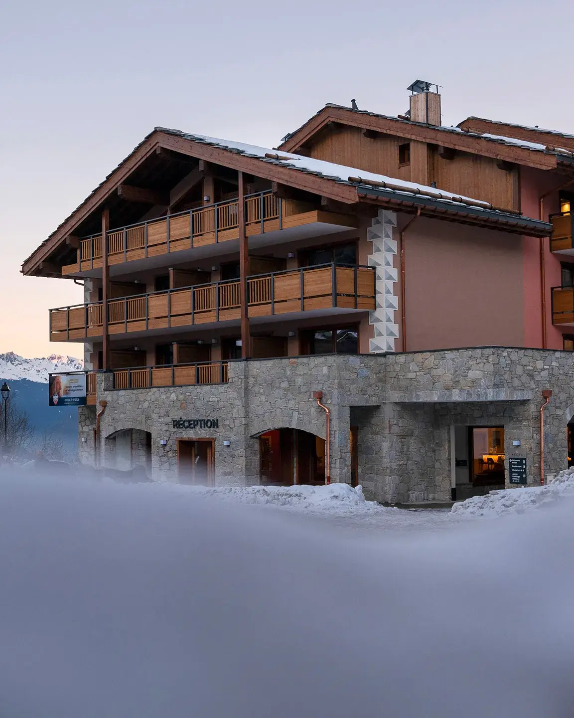 Vue sur la résidence Akoya à Valmorel en fin de journée, par un paysage enneigé