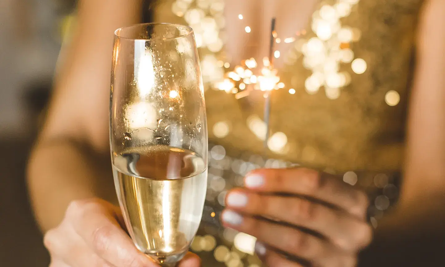 Une femme en robe dorée porte une coupe de champagne 