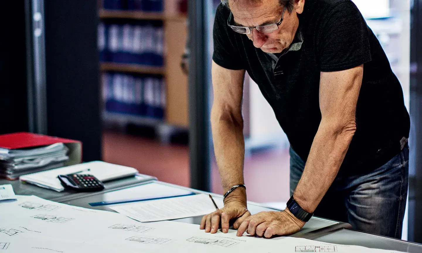 Un homme est en train de travailler sur des plans d'architectes dans un bureau