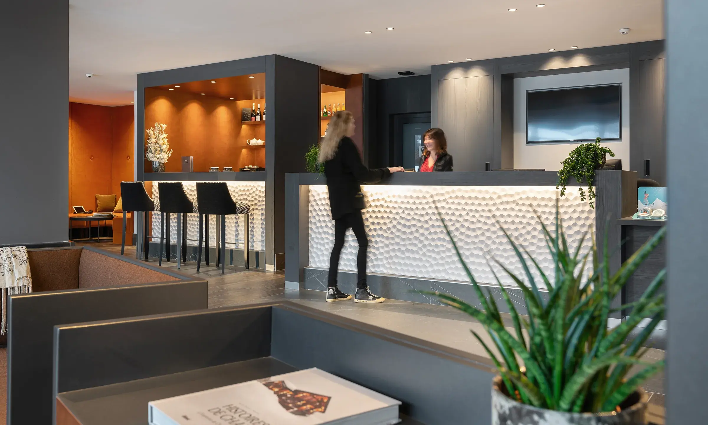 Une personne est au comptoir de la réception des Chalets Láska aux Contamines-Montjoie